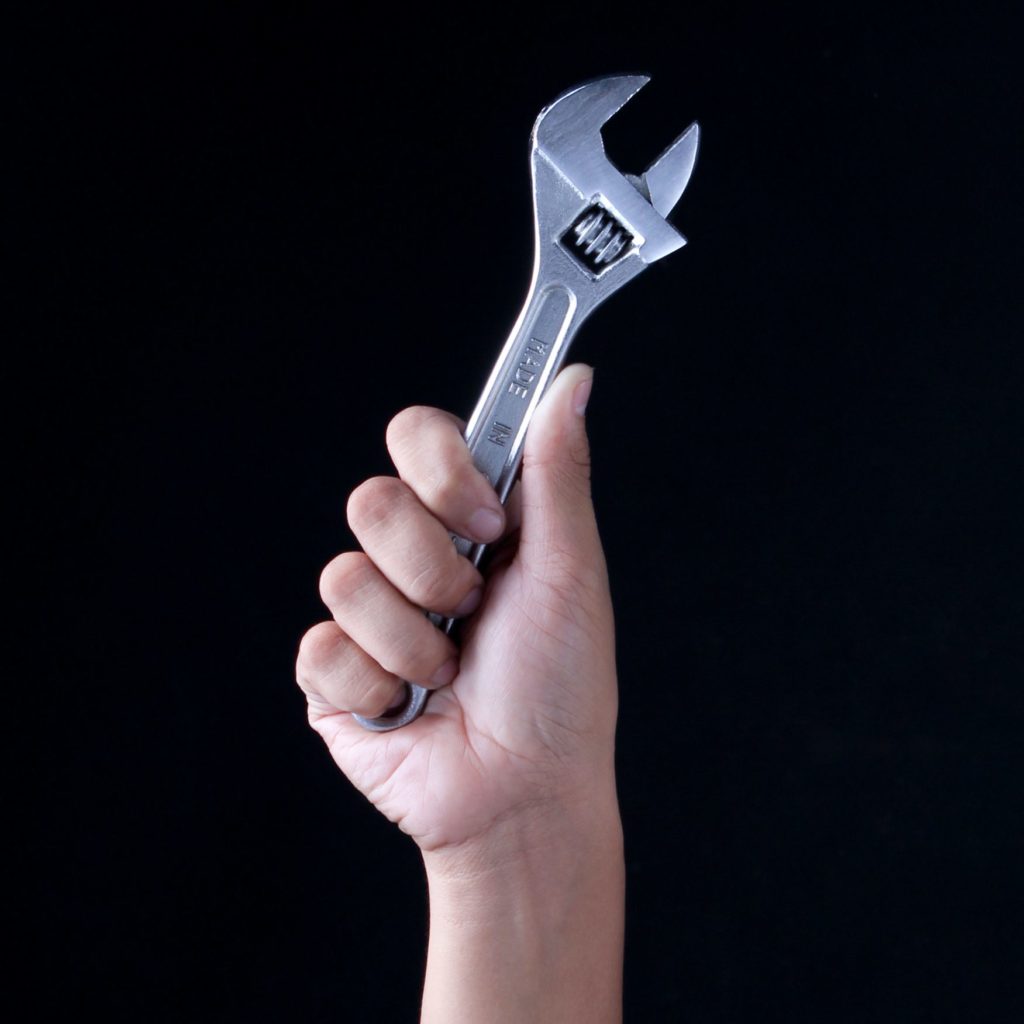 Image of hand with wrench to symbolize maintenance and repair for minimizing downtime.